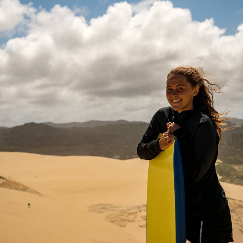 Zoe holding her Sandboard on the dunes